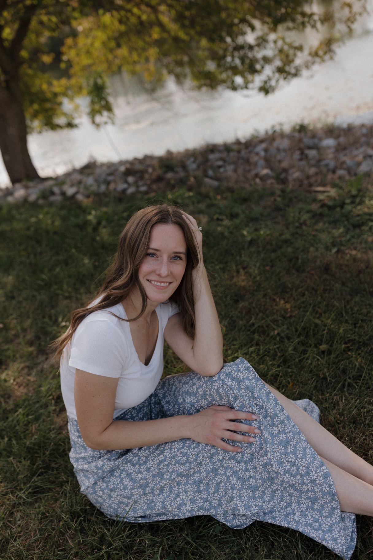 Ariel sitting by the water in a blue floral skirt